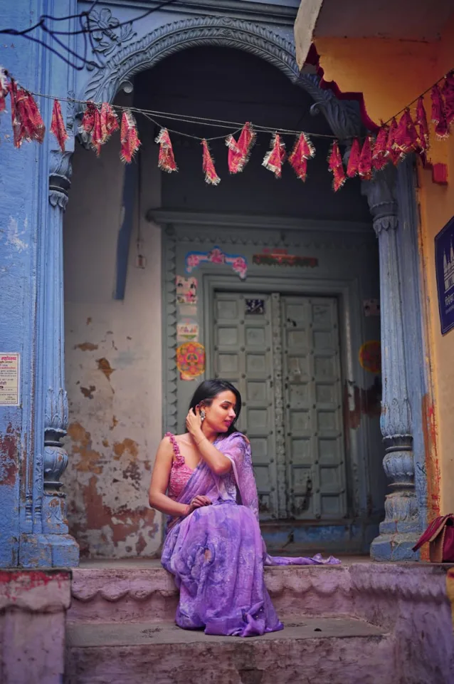 A visitor photographed by lamplight as dusk settles on the ghats, photographed by One Moon Studio in Varanasi.
